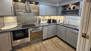 Une cuisine moderne dotée d’appareils électroménagers en acier inoxydable, de meubles de couleur grise et d’un plancher en bois.