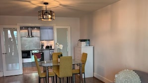 Un salon moderne comprenant un coin repas, un canapé gris, un tapis à motifs et un luminaire suspendu au plafond.
