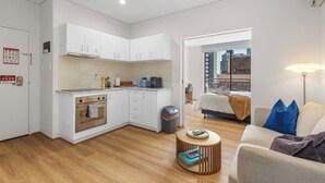 Un espacio habitable compacto con kitchenette, comedor y dormitorio.