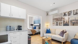 Un espacio habitable compacto con kitchenette, cama, sofá y mesa de centro.