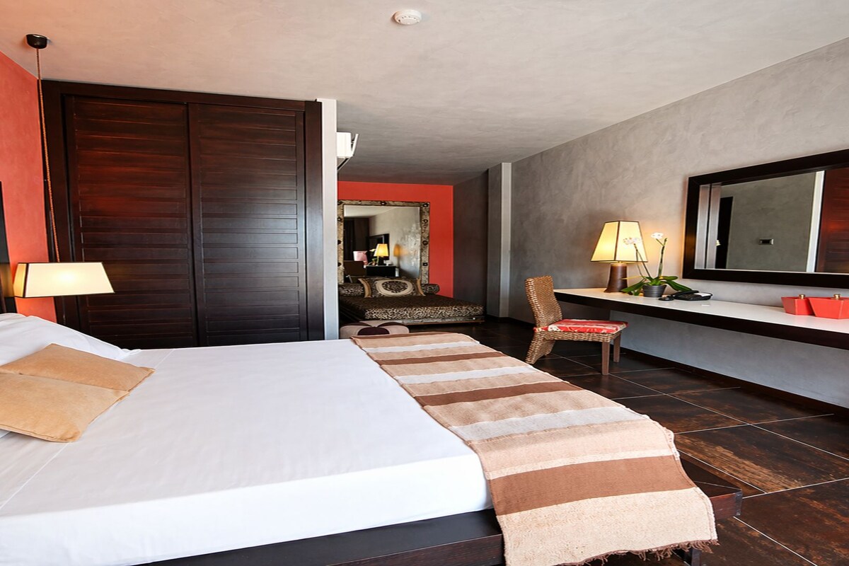 Une chambre d’hôtel avec un lit, un bureau, une chaise, une télévision et un miroir.