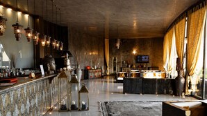Zona de bar con lámparas colgantes, suelo pulido y un área de estar con sofá y mesa de centro.