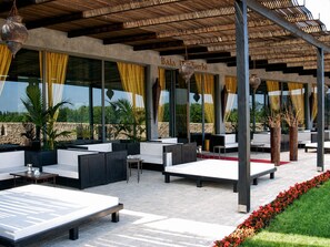 An outdoor seating area with tables and chairs, a pergola structure, and a view of the landscape.