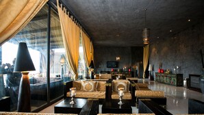 A modern lounge with sofas, tables, and a large window with curtains. - Hotiday Otranto Baia Resort (Otranto)
