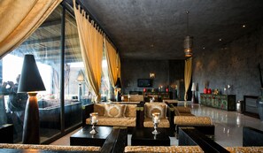 Un salón moderno con sofás, mesas y un amplio ventanal con cortinas.