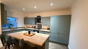 Una cocina moderna con una isla central, armarios oscuros e iluminación empotrada.