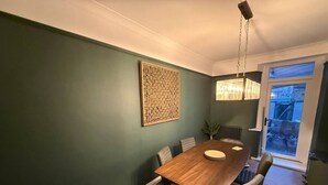 Un comedor con mesa de madera, sillas, lámpara colgante y un adorno en la pared.