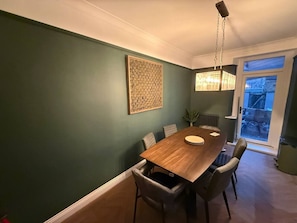 Ein Essbereich mit Holztisch, Stühlen, einer Hängelampe und einem Wanddekor.