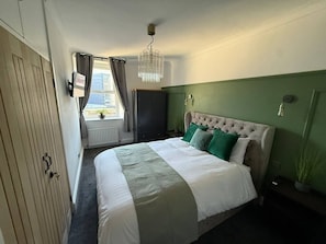 Ein Schlafzimmer mit einem Bett, einer Chandelier, einem Fenster mit Vorhängen und einer Heizung.