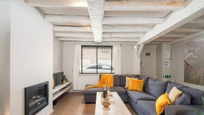 Una sala de estar moderna con chimenea, un conjunto de sofás, una mesa de centro y un ventanal con persianas.