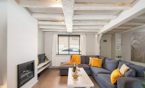 A modern living room with a fireplace, a sofa set, a coffee table, and a large window with blinds. - Duinhalm - located in the heart of Nieuwpoort (Nieuwpoort)