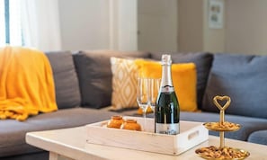 A bottle of wine, glasses, and a tray with snacks on a wooden table in a living room with a sofa and cushions. - Duinhalm - located in the heart of Nieuwpoort (Nieuwpoort)
