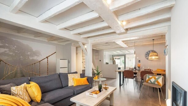 Una sala de estar moderna con sofá, mesa de centro y comedor con sillas.