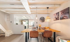A modern dining area with a wooden table, two chairs, a hanging light fixture, and a wall clock. - Duinhalm - located in the heart of Nieuwpoort (Nieuwpoort)