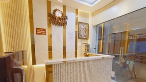 A reception desk with a marble design, a clock, and a sign for 'HOTEL KRISHNA Check Out Time-9 am.' - Hotel Shree Krishna Inn (Ujjain)