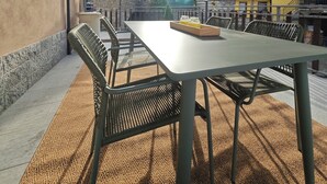 An outdoor patio with a table and chairs, a view of a mountain, and a building in the background. - "Al Planet" Mountain Lodging: Hiking and Golf (Fiou)