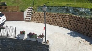 A view of a mountainous landscape with a small wooden structure and a paved area with planters. - "Al Planet" Mountain Lodging: Hiking and Golf (Fiou)