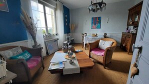 A cozy living room with a sofa, armchair, and coffee table, a dining table with chairs, and a decorative chandelier. - Beachfront home in Douarnenez Bay (Plonévez-Porzay)
