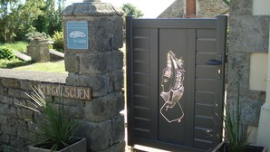 A stone wall with a sign reading 'KERCOISCUEN' and a decorative door with a relief of a figure. - Beachfront home in Douarnenez Bay (Plonévez-Porzay)