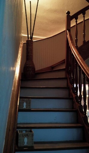Eine Treppe mit einer Holzhandläufe und einer Vase mit Zweigen an der Wand.