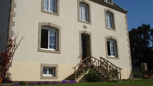 A multi-story building with a symmetrical facade, a central entrance, and a staircase leading to the entrance. - Beachfront home in Douarnenez Bay (Plonévez-Porzay)
