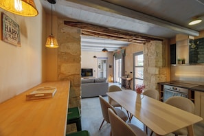 A cozy interior with a wooden dining table, a sofa, and a kitchen area.