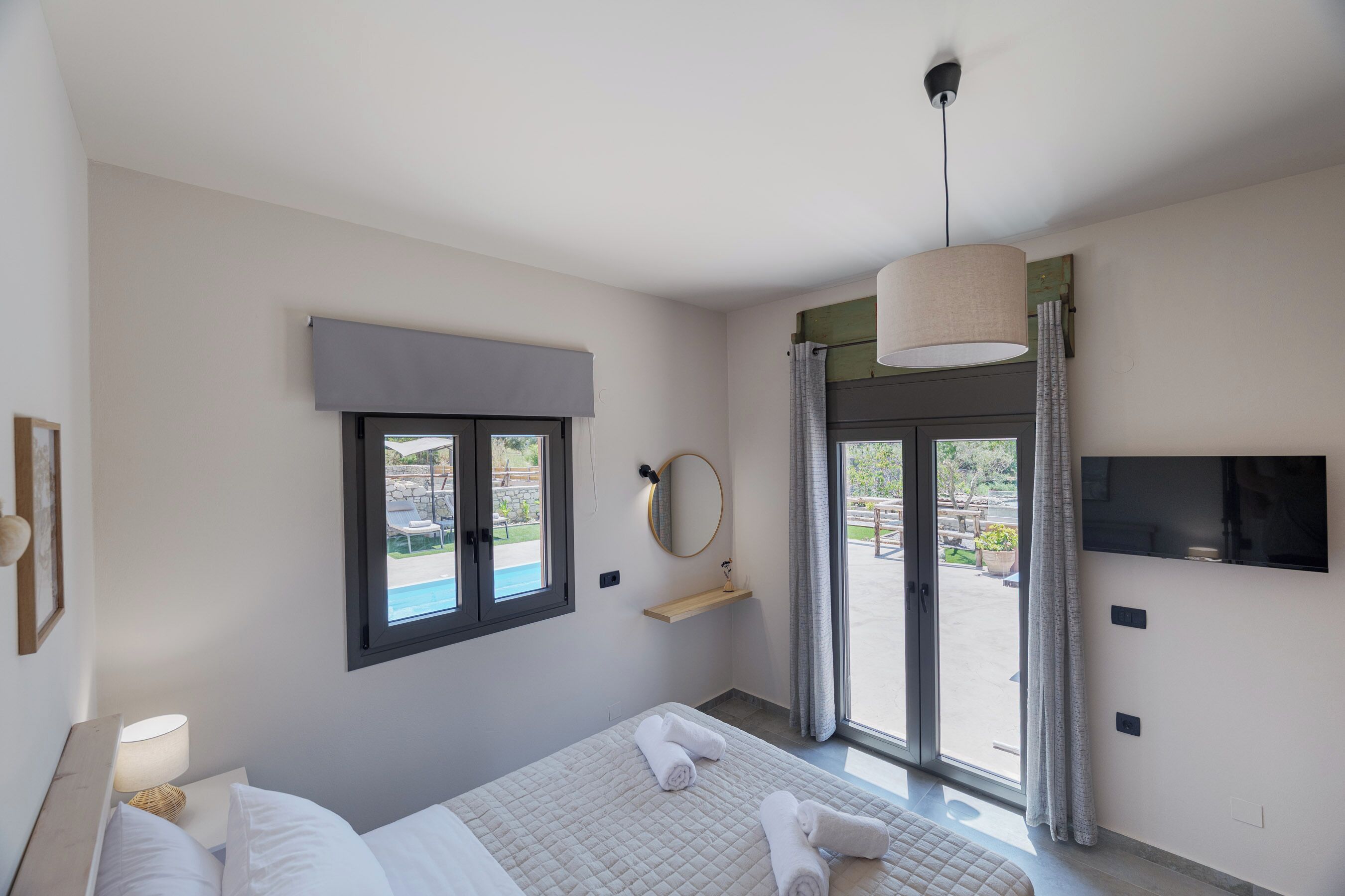 A hotel room with a bed, a TV, a window, and a view of the outside.