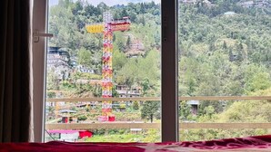 A window view of a mountainous area with a construction crane. - Shubh Hotel (Mussoorie)