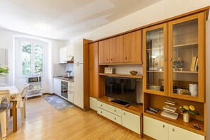 A modern kitchen with wooden cabinets, a built-in TV, and a dining area with a table and chairs.