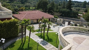 A courtyard with a tiled-roof building, palm trees, and a curved balcony.