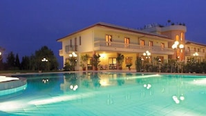 A large, multi-story hotel with a swimming pool, balconies, and outdoor lighting.