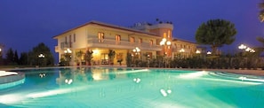 A large, multi-story hotel with a swimming pool, balconies, and outdoor lighting. - Hotiday Corato (Corato)