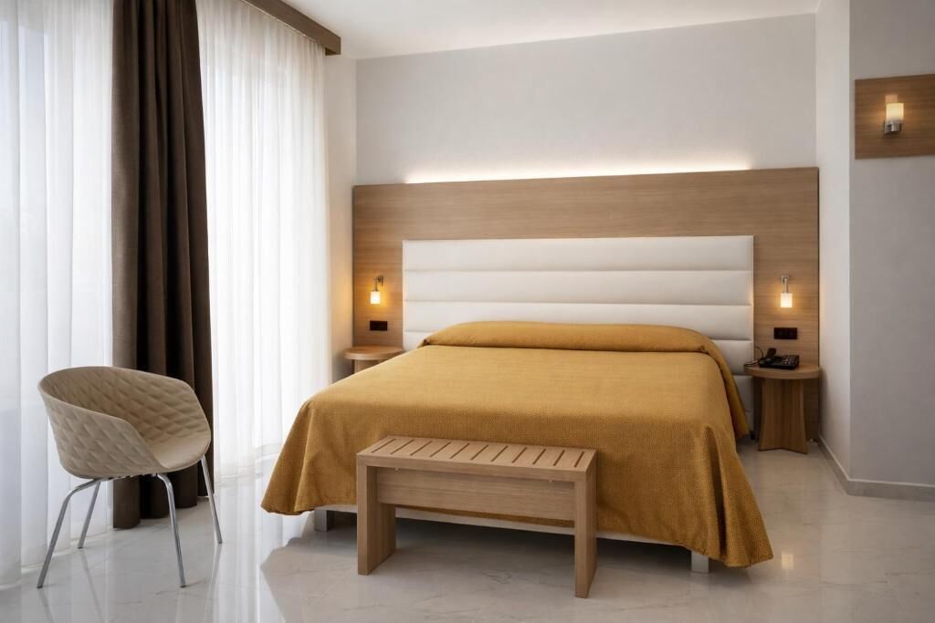 A modern bedroom with a large bed, bedside tables, a chair, and a bench.