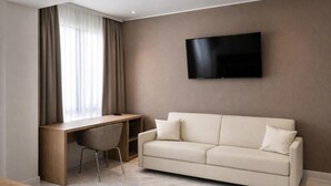 A modern room with a sofa, a desk, and a TV mounted on the wall.