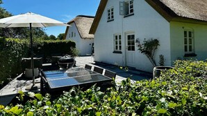 Una casa con techo de paja, piscina y mobiliario exterior.