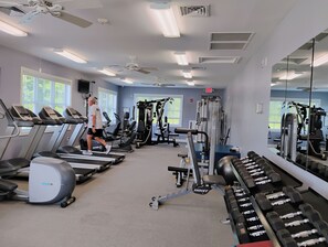 A gym with treadmills, weight machines, and dumbbells.