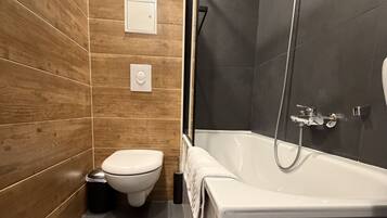 Une salle de bain moderne avec un meuble-lavabo en bois, des toilettes blanches, une baignoire et un espace douche.