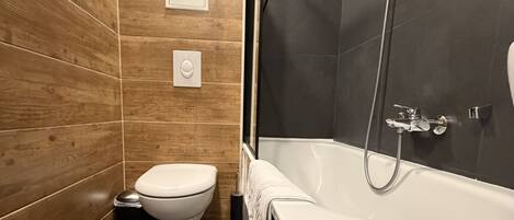 Une salle de bain moderne avec un meuble-lavabo en bois, des toilettes blanches, une baignoire et un espace douche.