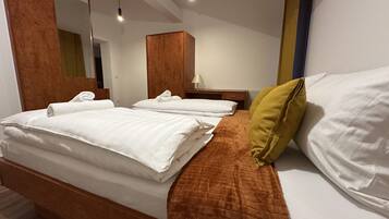 A hotel room with a bed, a nightstand, a lamp, a mirror, and a wooden wardrobe.