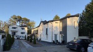 Rua residencial com casas, carros estacionados e céu claro.