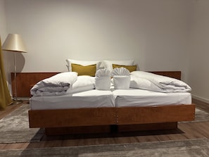 Ein ordentlich bezogenes Bett mit weißen Leinen, einem Holzkopfteil und einer Nachttischlampe.