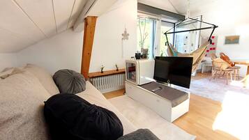 Ett modernt vardagsrum med en soffa, en tv, en hängstol och en matplats med stolar och ett bord.