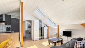 A modern loft-style apartment with a kitchen, dining area, and living room, featuring skylights and wooden beams. - Panorama Loft – Scenic Views & Active Getaway at the Foot of the Swabian Alb (Lichtenstein)