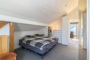 Een slaapkamer met een bed, een stoel, een kledingkast en uitzicht op een balkon.
