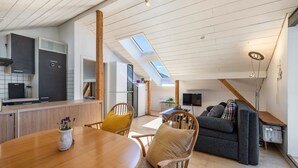 A modern kitchen with skylights, a dining area with wooden furniture, and a cozy living space with a sofa and TV. - Panorama Loft – Scenic Views & Active Getaway at the Foot of the Swabian Alb (Lichtenstein)