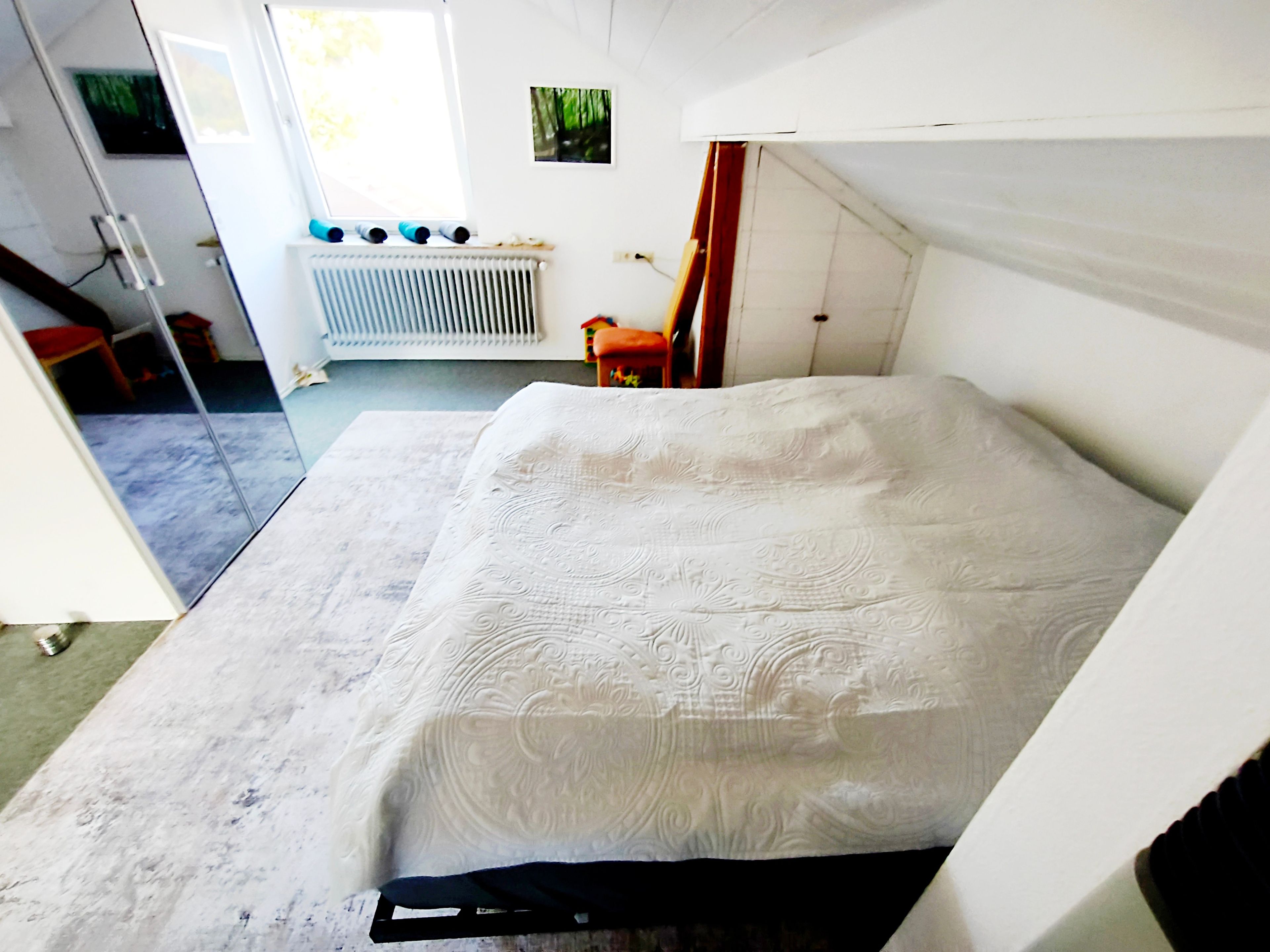 A room with a bed, a radiator, a window, and a door.