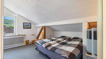 A bedroom with a bed, a radiator, a window with a view, and a heater.