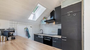 A modern kitchen with a wooden countertop, black cabinets, a built-in oven, and a skylight. - Panorama Loft – Scenic Views & Active Getaway at the Foot of the Swabian Alb (Lichtenstein)