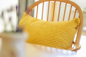 Una silla de madera con un cojín amarillo con textura.