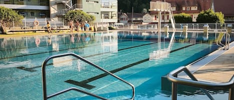 Una piscina con agua cristalina, barandillas de metal y un borde de baldosas.